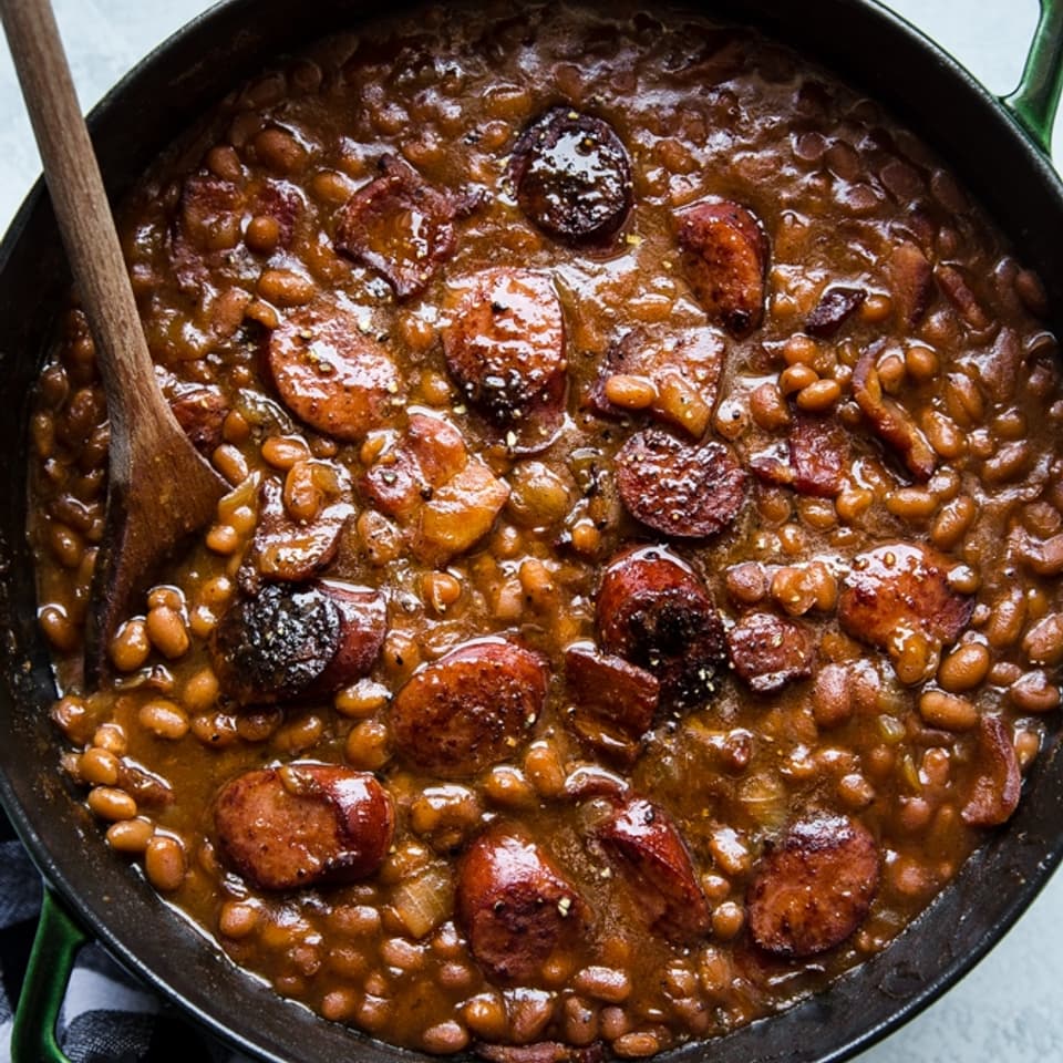 baked beans in a pot with made with extra ketchup, mustard, brown sugar and sausage.