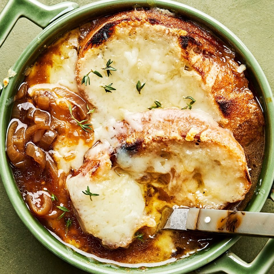 a bowl of homemade french onion soup topped with warm, bubbly Gruyère cheese