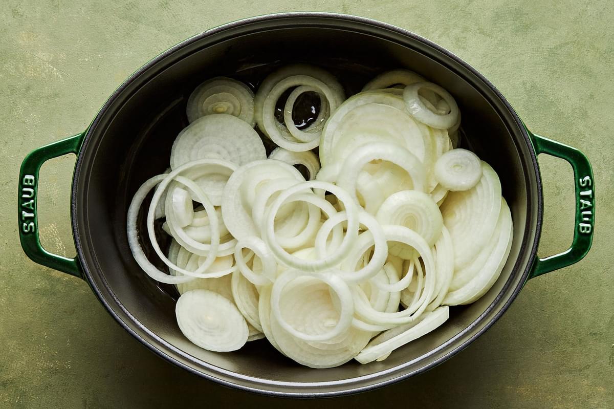 sliced onions being caramelized in olive oil in a pot for french onion soup