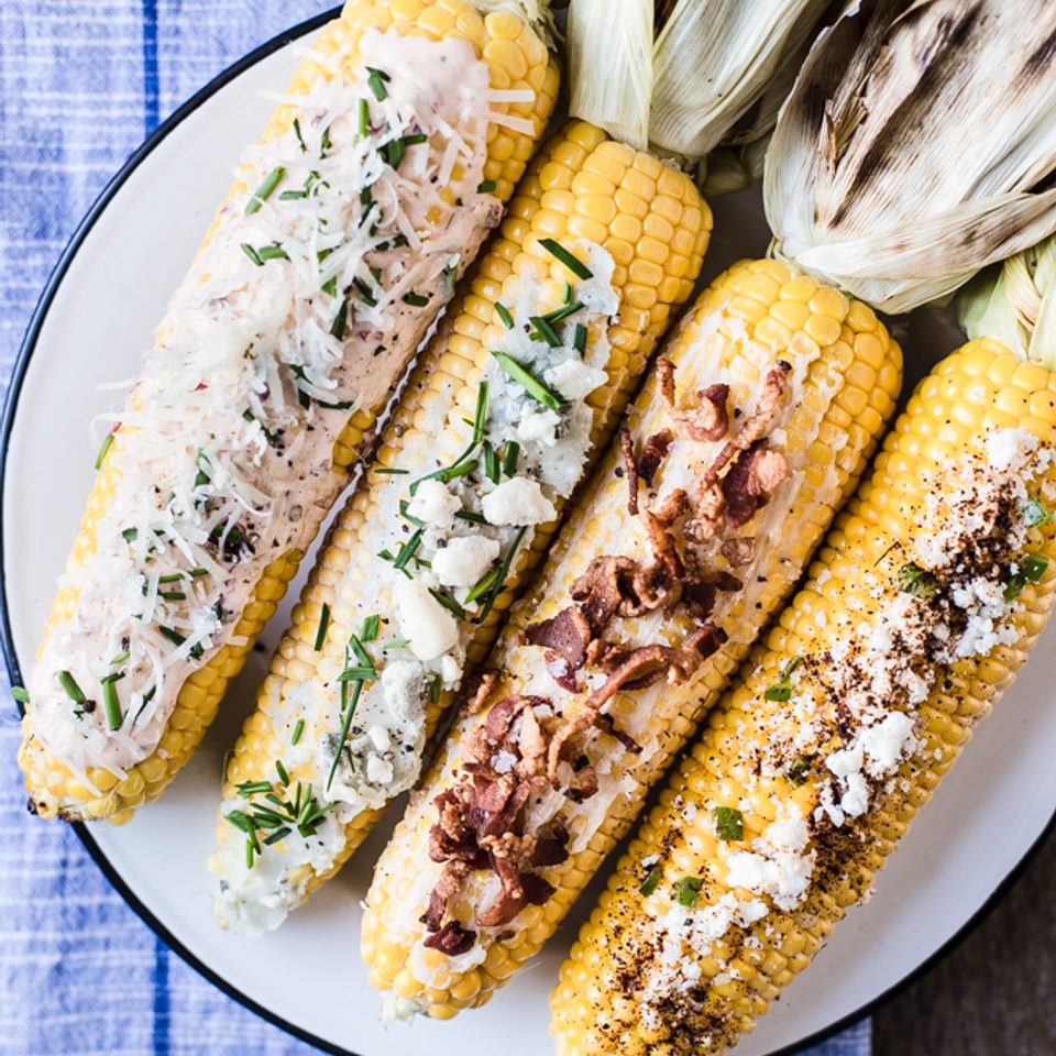 grilled corn on the cob with 4 toppings ideas on a plate