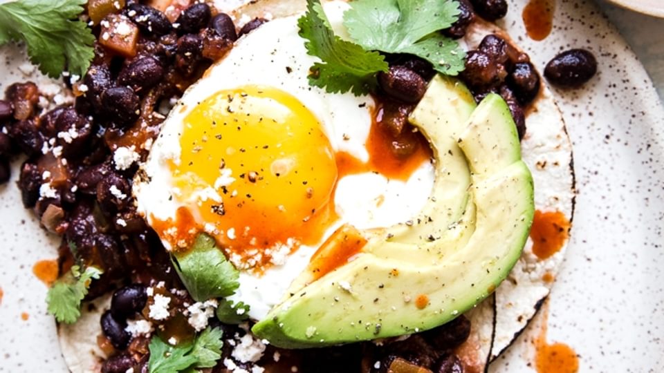 Huevos rancheros on a plate with beans ann egg and avocado