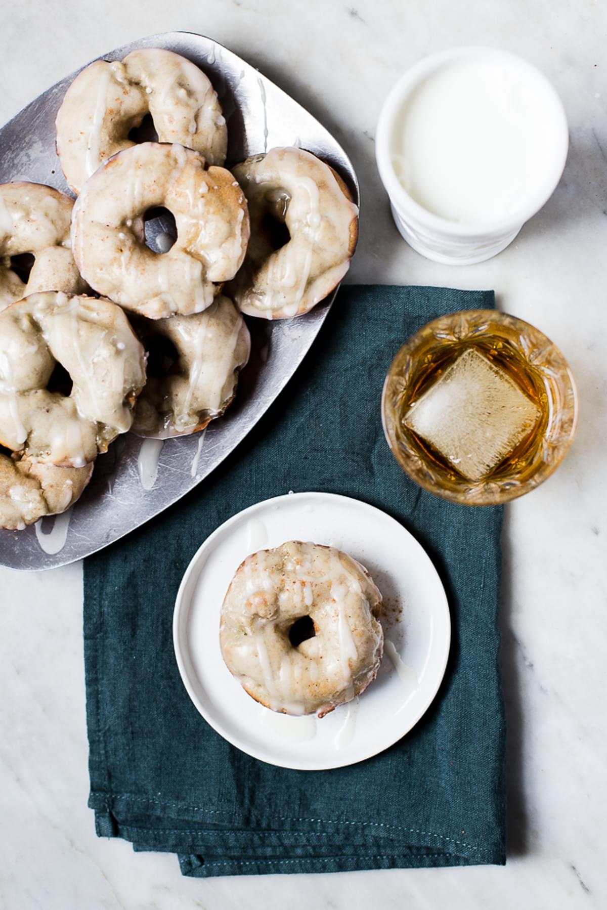 Irish Apple Cake Donuts with Whiskey Glaze with a glass of milk and a glass of whiskey