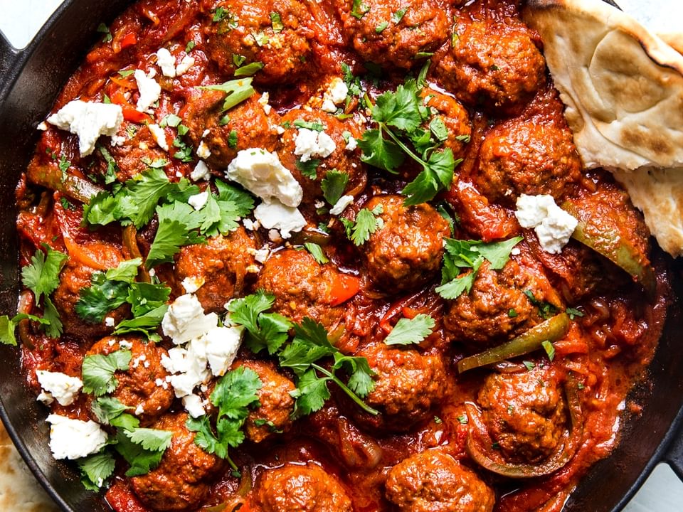 spiced meatballs in a shakshuka in a ban with feta and pita bread