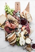 Cheese charcuterie board with grapes, apples, honey, nuts and bread