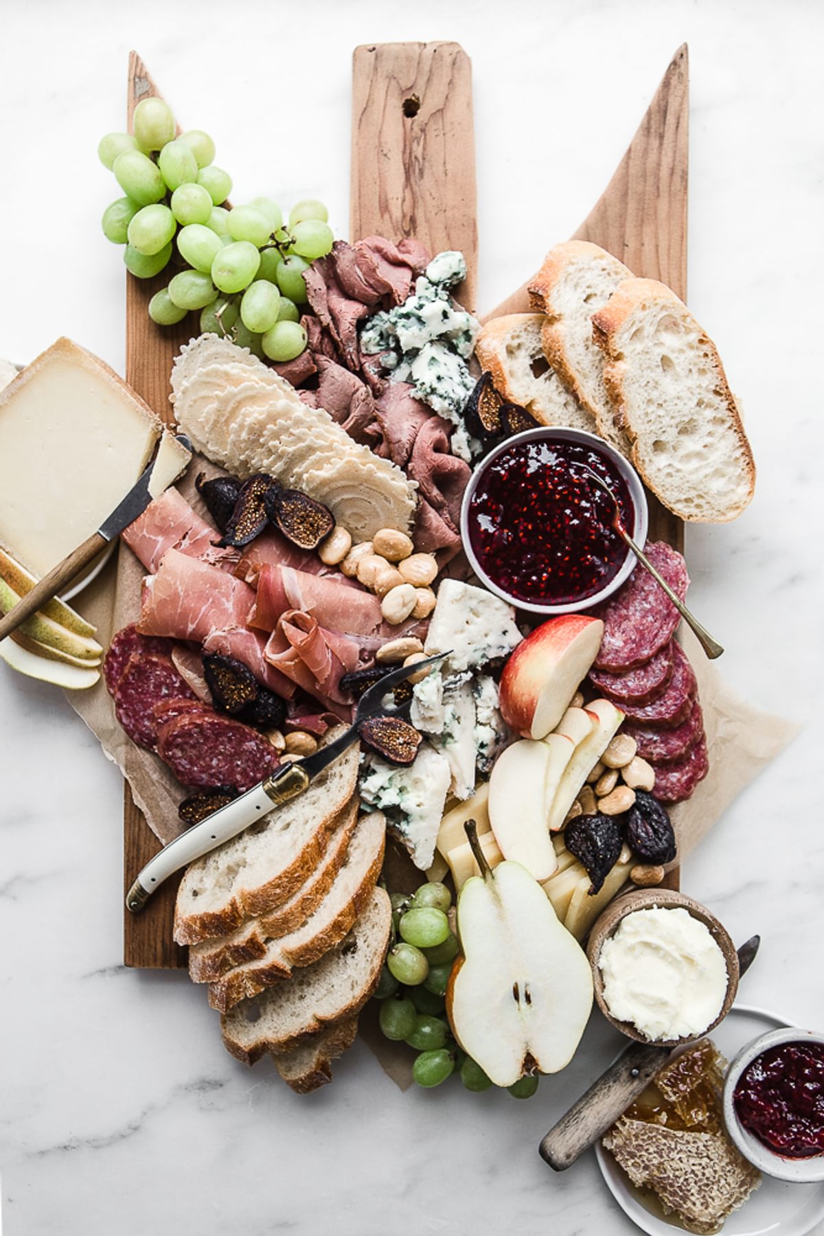 Cheese charcuterie board with grapes, apples, honey, nuts and bread