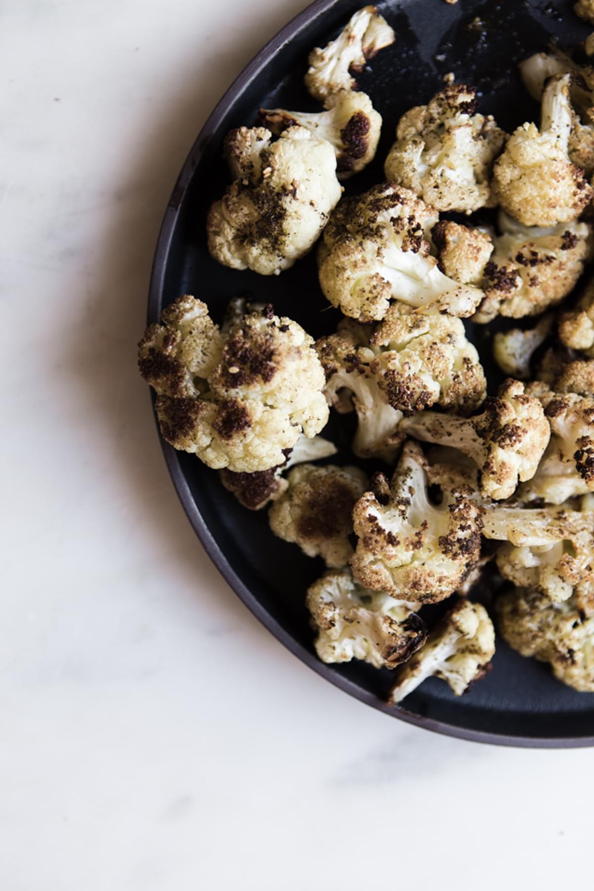 a bowl of roasted cauliflower with za'atar on a plate