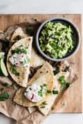 Roasted Poblano and Carnitas Quesadillas with guacamole in a bowl served with lime wedges and radish