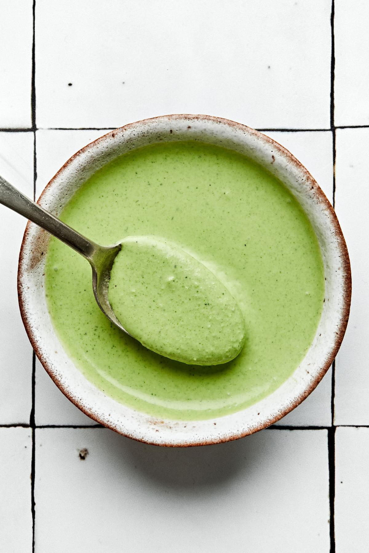 homemade green goddess dressing in a bowl being scooped with a spoon