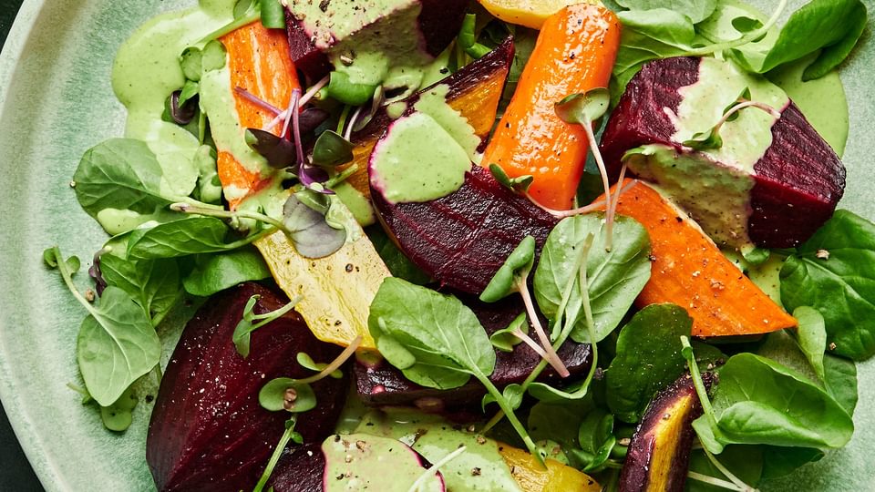 Roasted beet salad made with beets, carrots, spring salad mix and micro greens drizzled with green goddess dressing