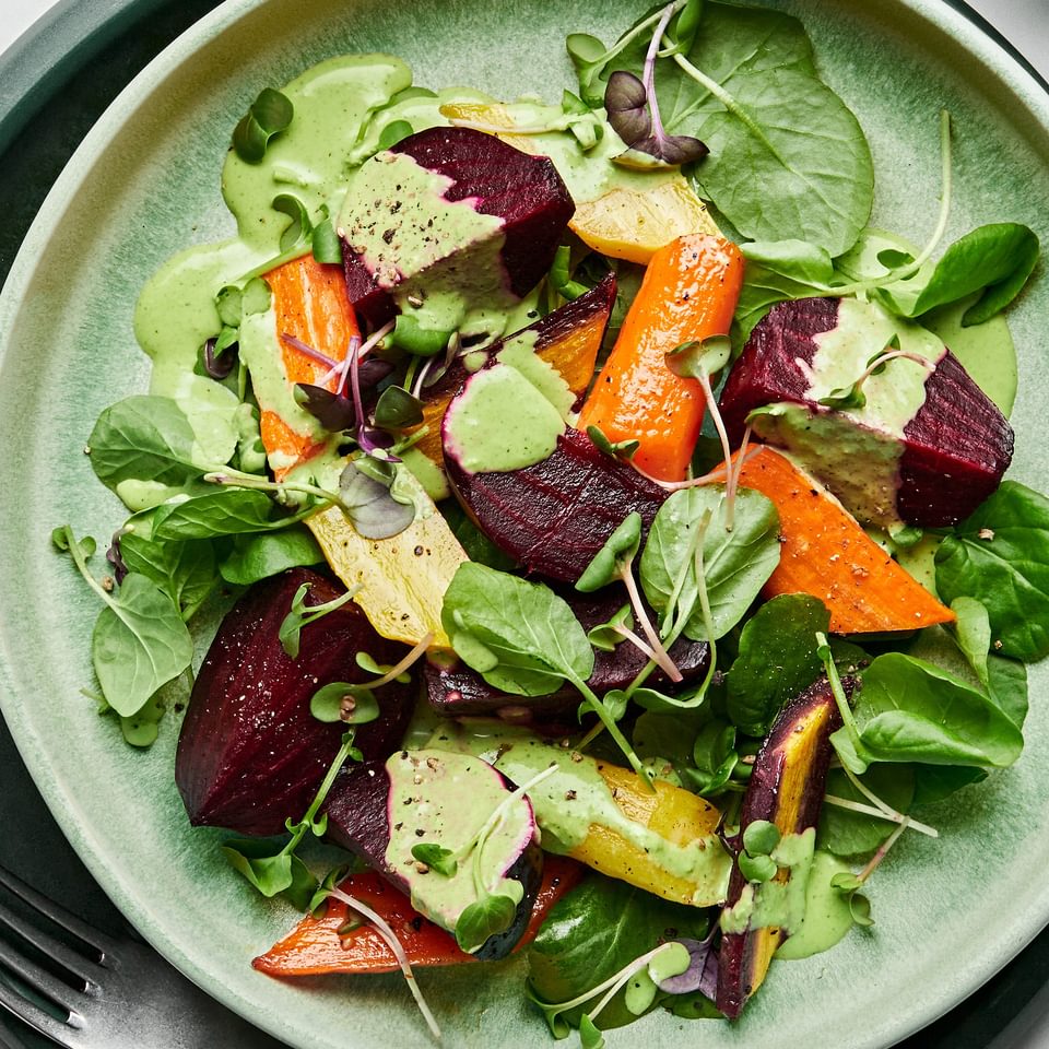 Roasted beet salad made with beets, carrots, spring salad mix and micro greens drizzled with green goddess dressing