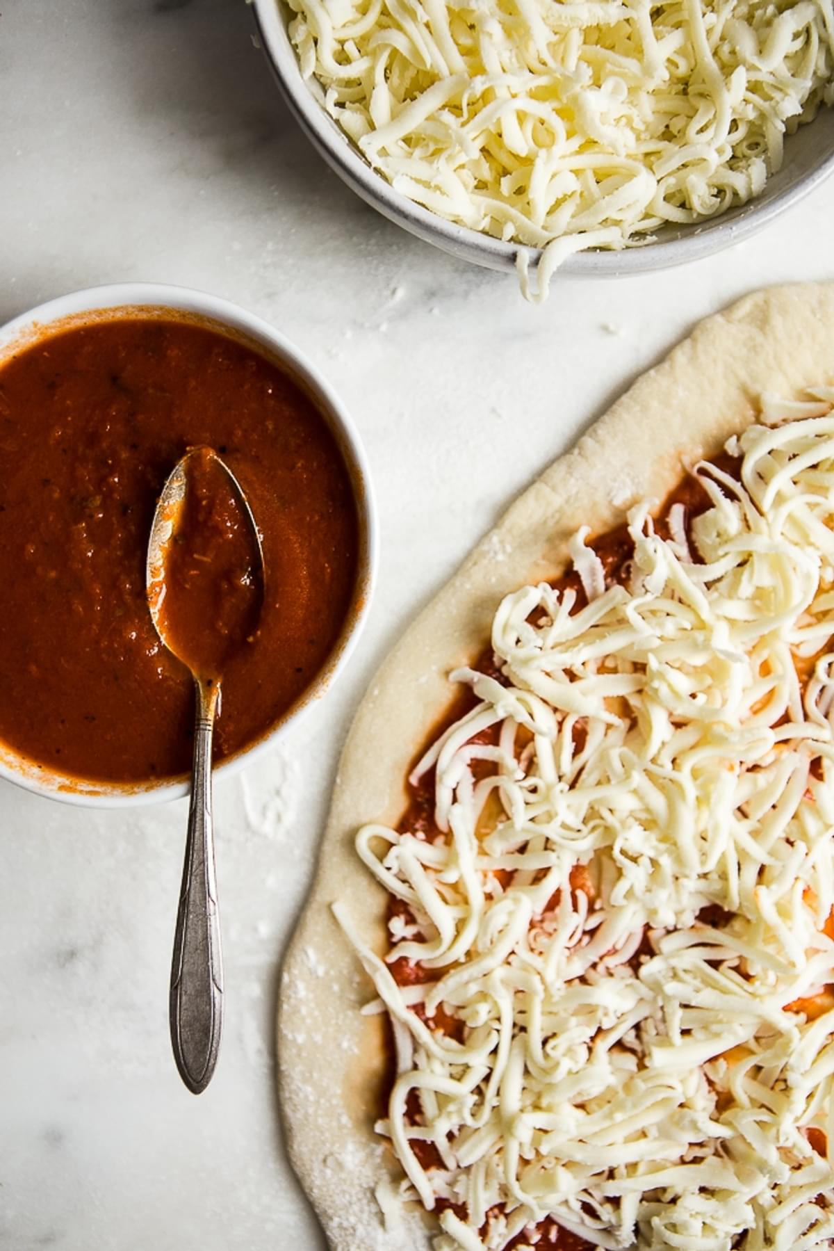 pizza crust with sauce and shredded mozzarella cheese