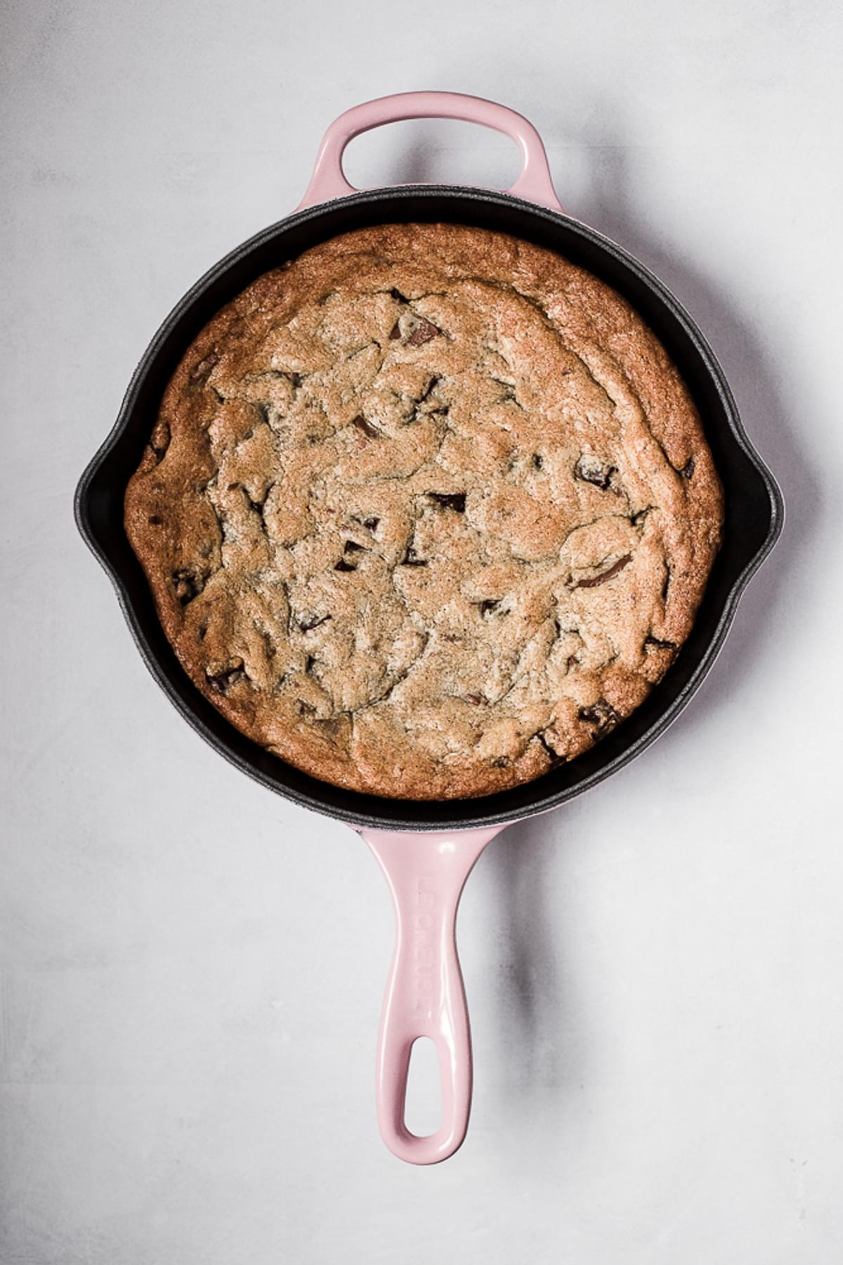 freshly baked chocolate chip skillet cookie in a pink cast iron skillet