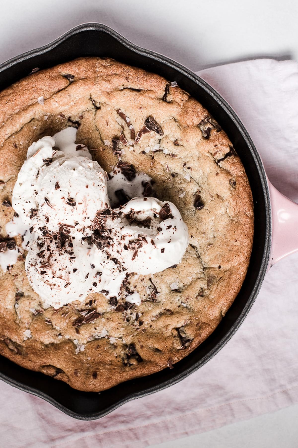 Salty Dark and Milk Chocolate Skillet Cookie in a cast iron pan with ice cream