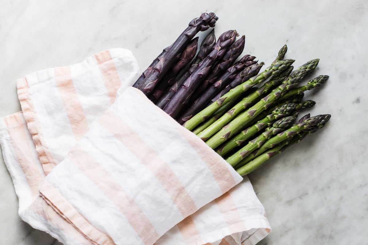 purple and green asparagus wrapped in a linen.