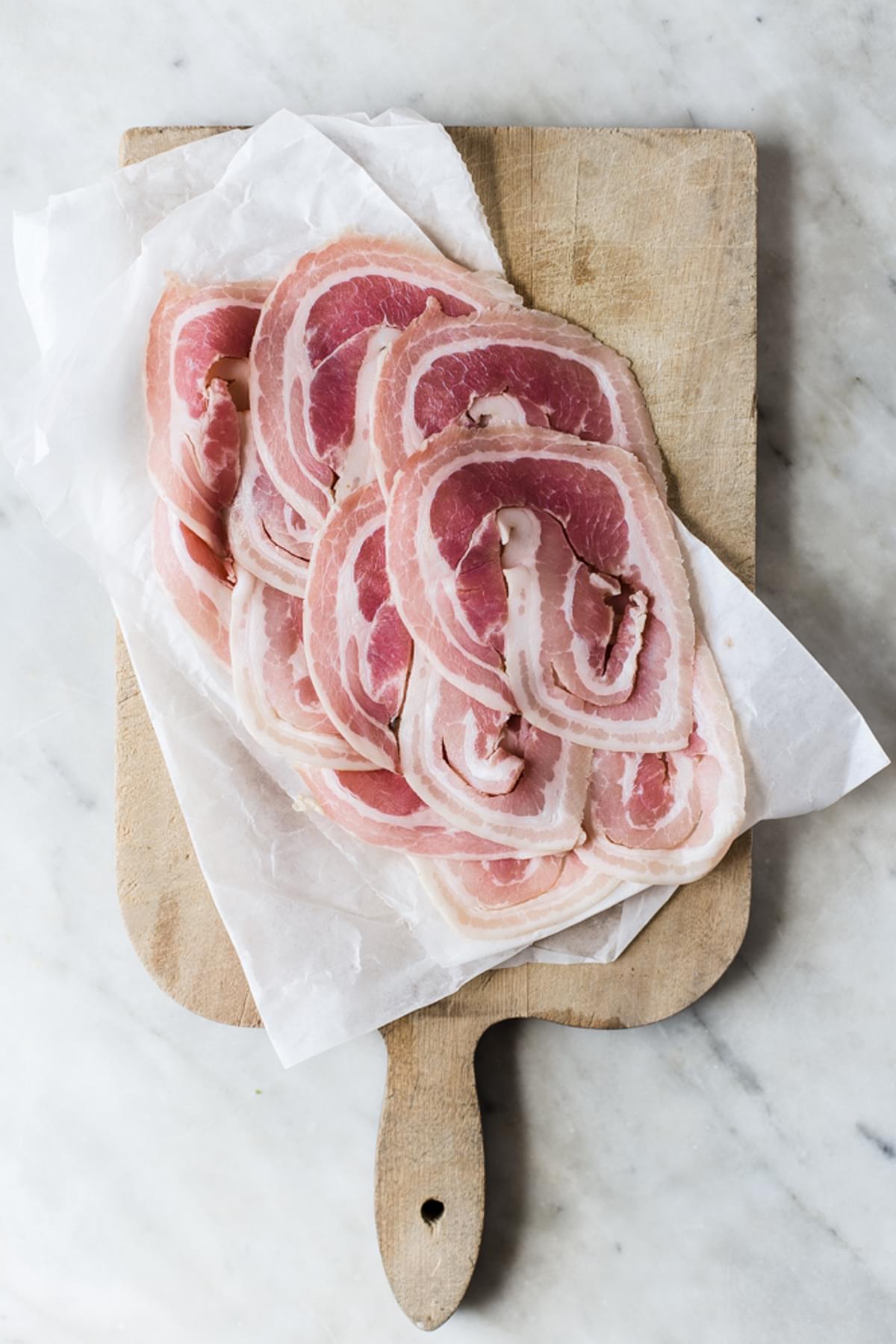 pancetta on parchment paper on a cutting board.