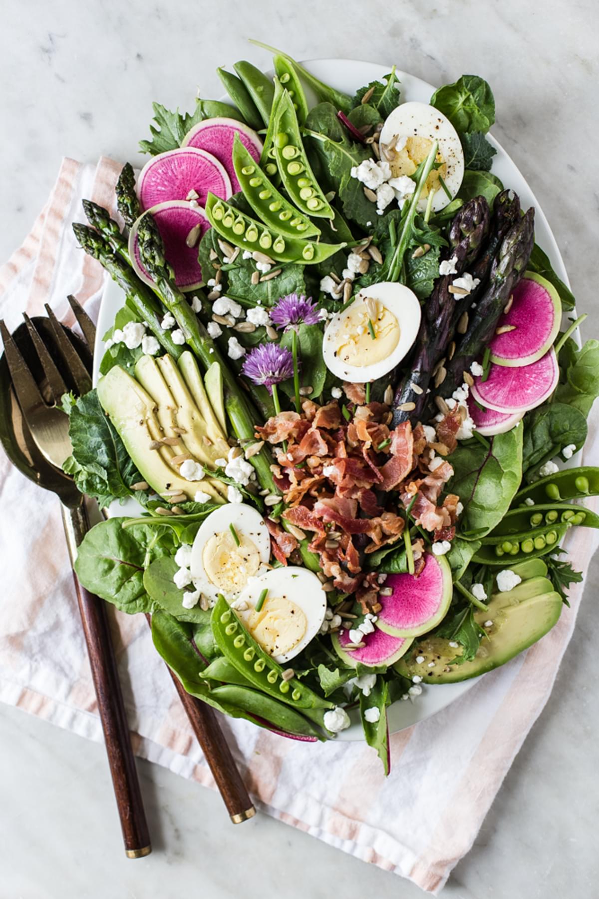 Spring cobb salad on a plater with pancetta, goat cheese, sunflower seeds, asparagus avocado radish and hard boiled eggs.