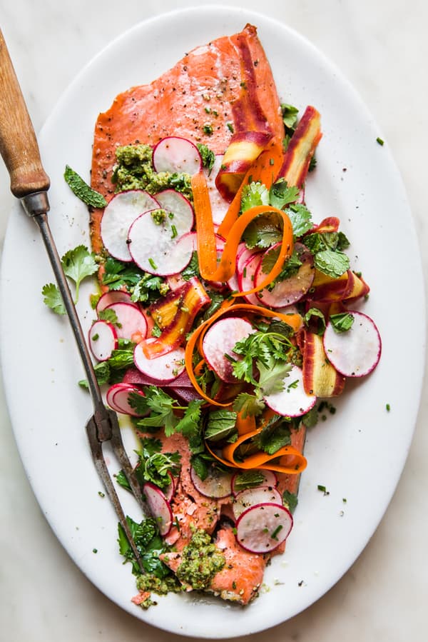 Roasted Salmon With Spring Pesto on a platter with radishes, mint, cilantro and carrot ribbons