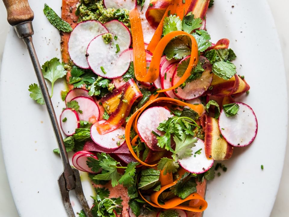 Roasted Salmon With Spring Pesto on a platter with radishes, mint, cilantro and carrot ribbons