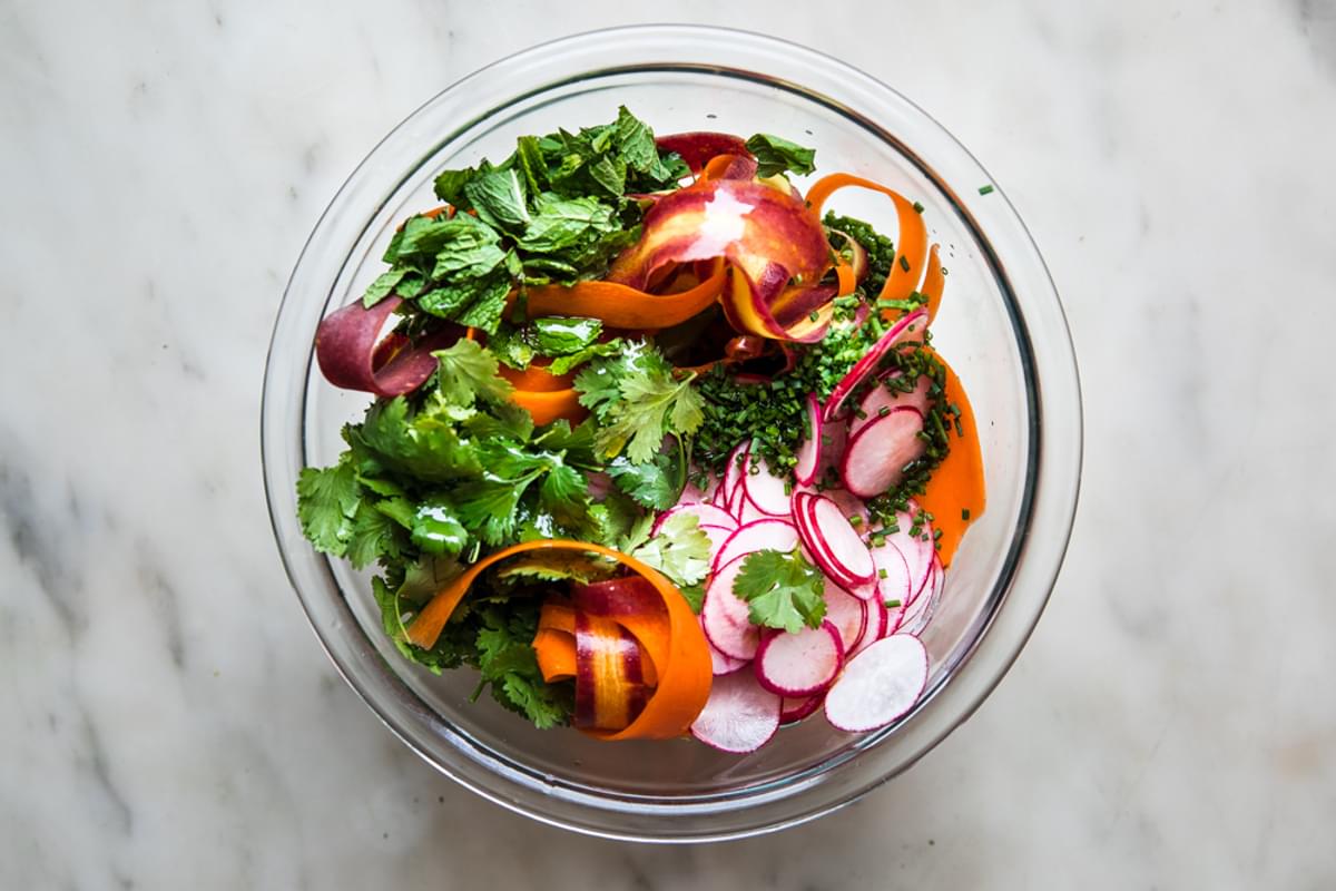 pea pesto in a bowl with carrot ribbons, radishes, mint and cilantro