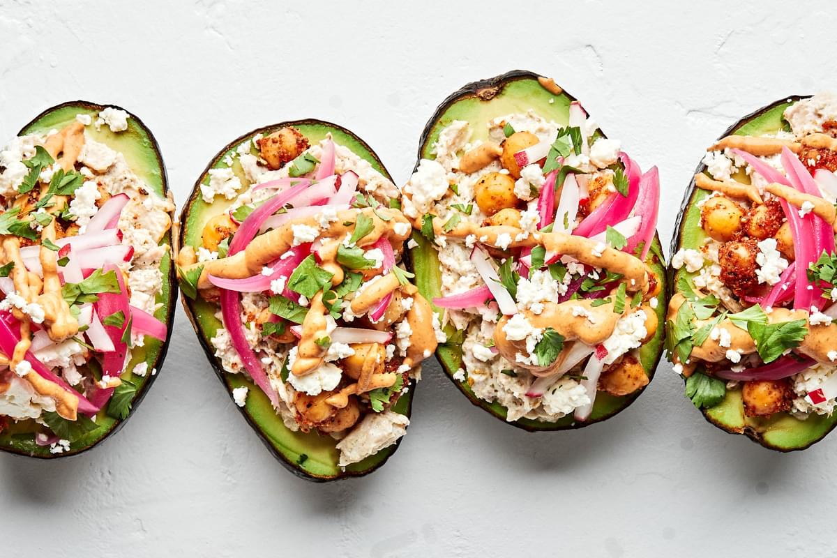 tuna salad stuffed avocados topped with pickled red onions, feta cheese and vegan cashew cheese
