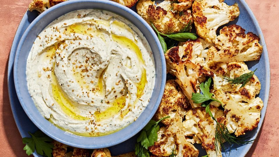 za'atar roasted cauliflower on a serving platter with a bowl of herb whipped feta