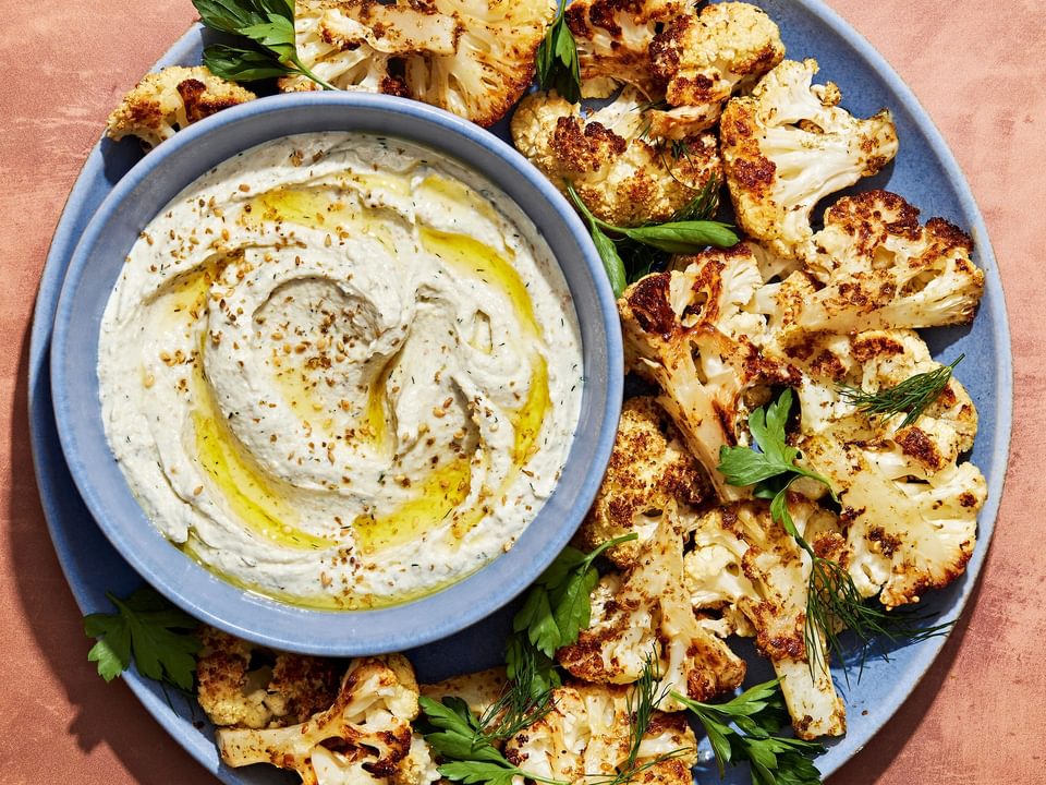 za'atar roasted cauliflower on a serving platter with a bowl of herb whipped feta