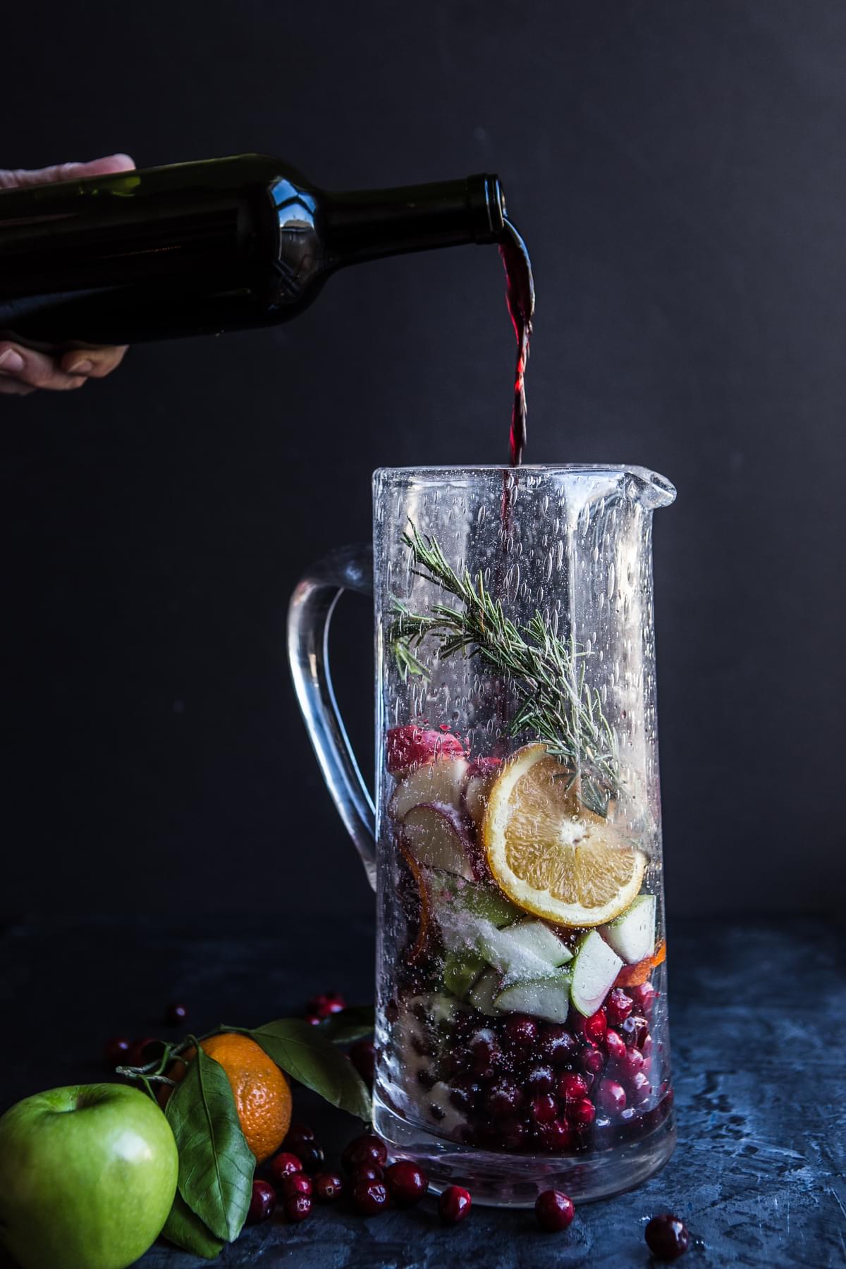apples, oranges, cranberries and rosemary, sugar and cinnamon in a pitcher for red sangria