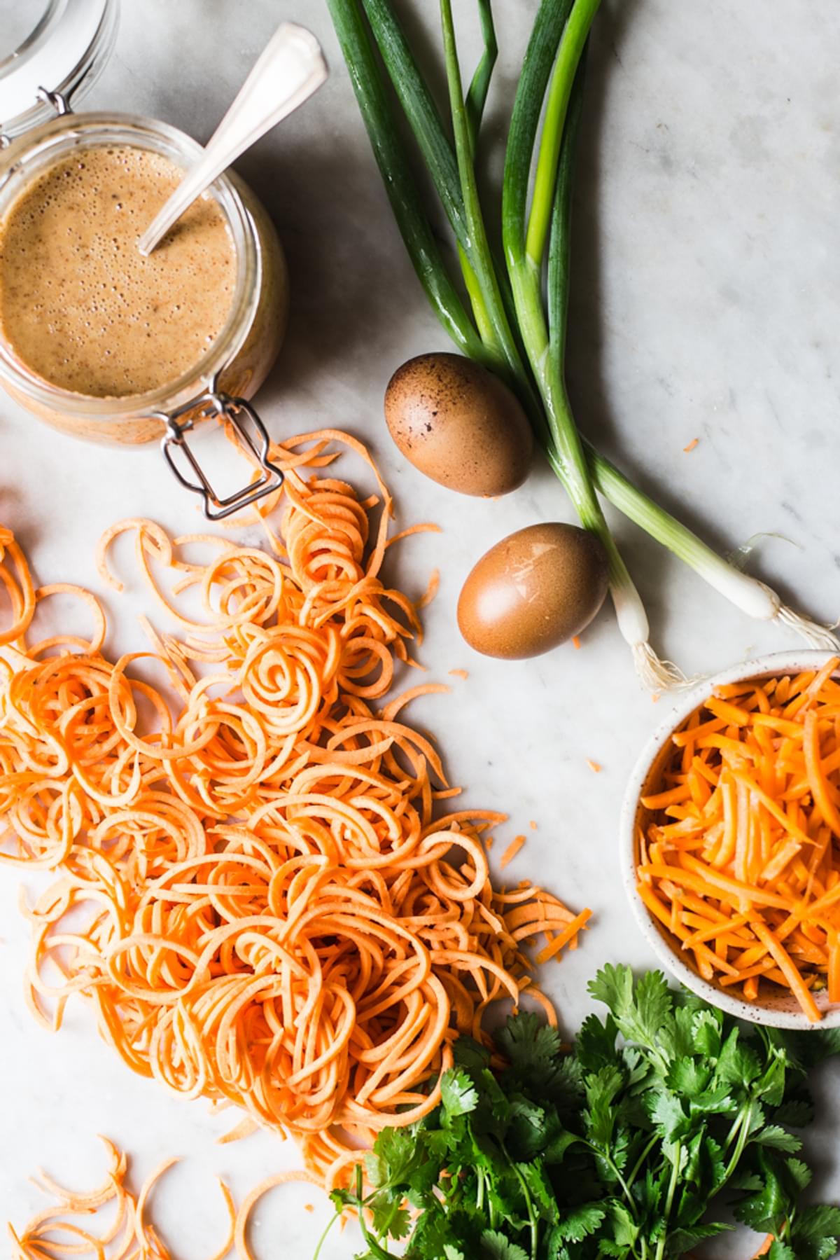 healthy pad Thai sauce next to sweet potatoes, cilantro green onions and eggs