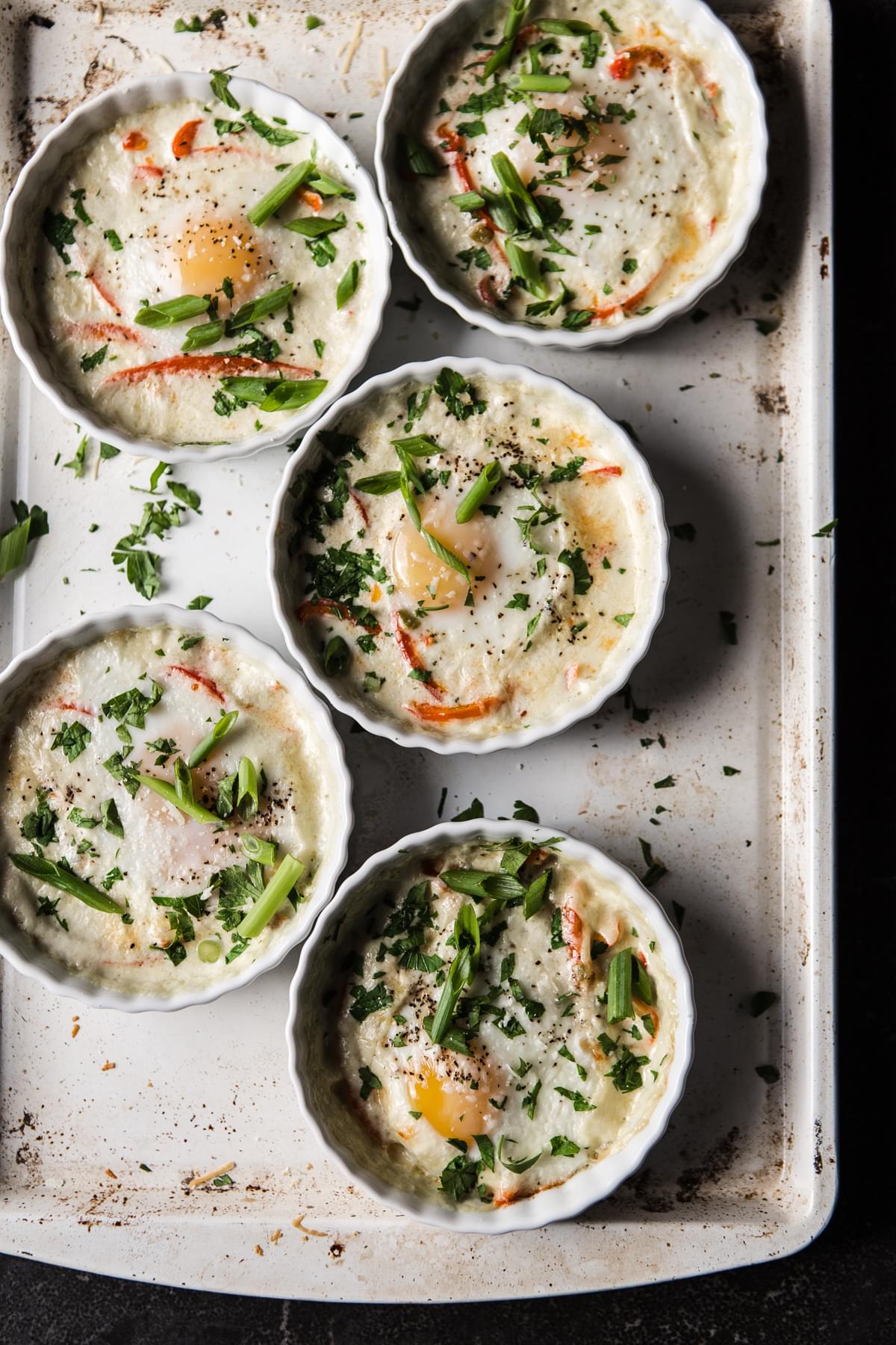 5 ramekins with eggs baked in cream with red bell peppers and leeks