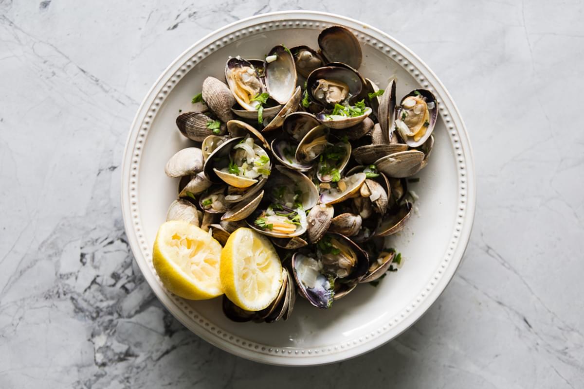 Steamed Clams With Linguini in a bowl with a lemon half