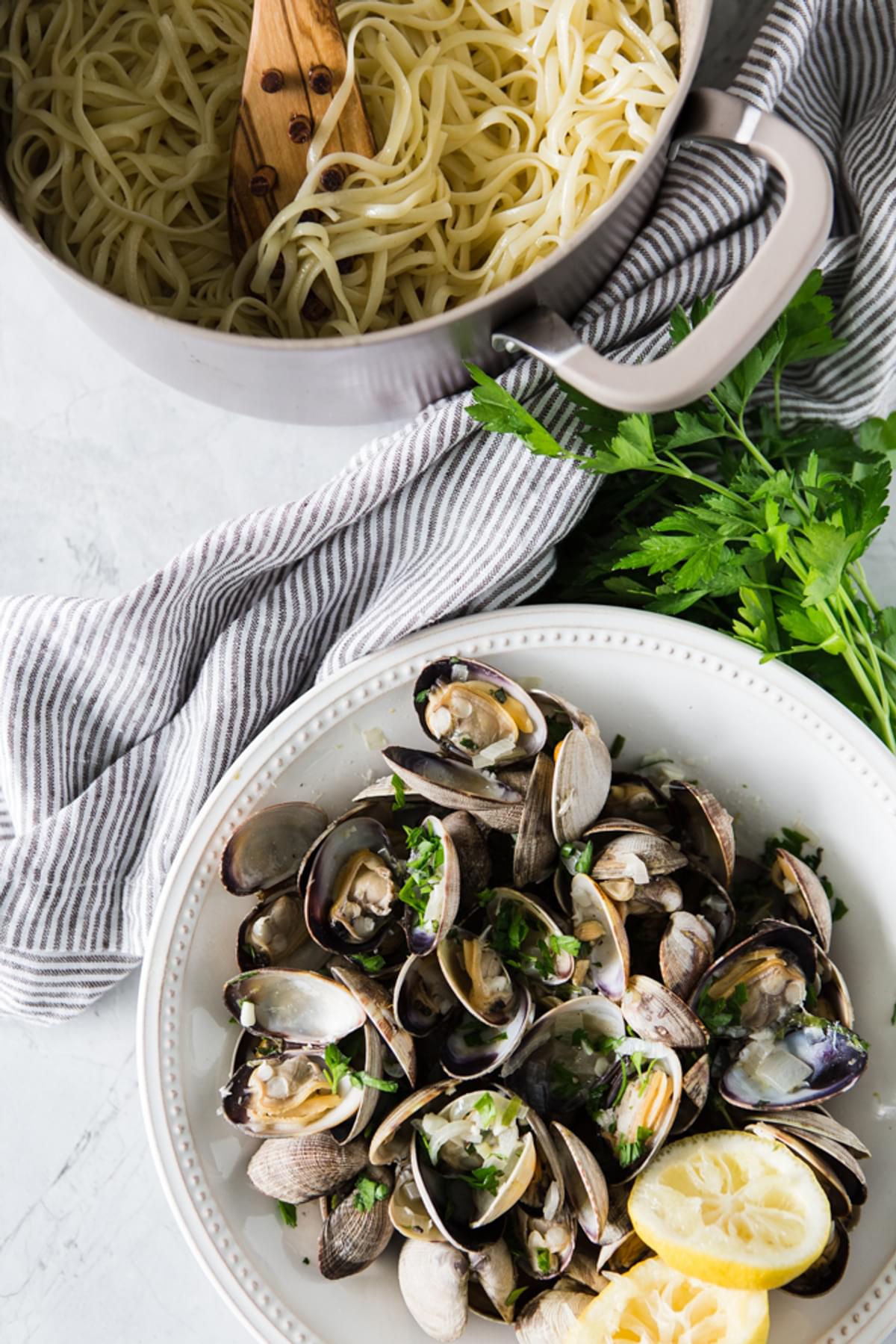 Steamed Clams With Linguini with cream and parmesan next to a pit of pasta and parsley