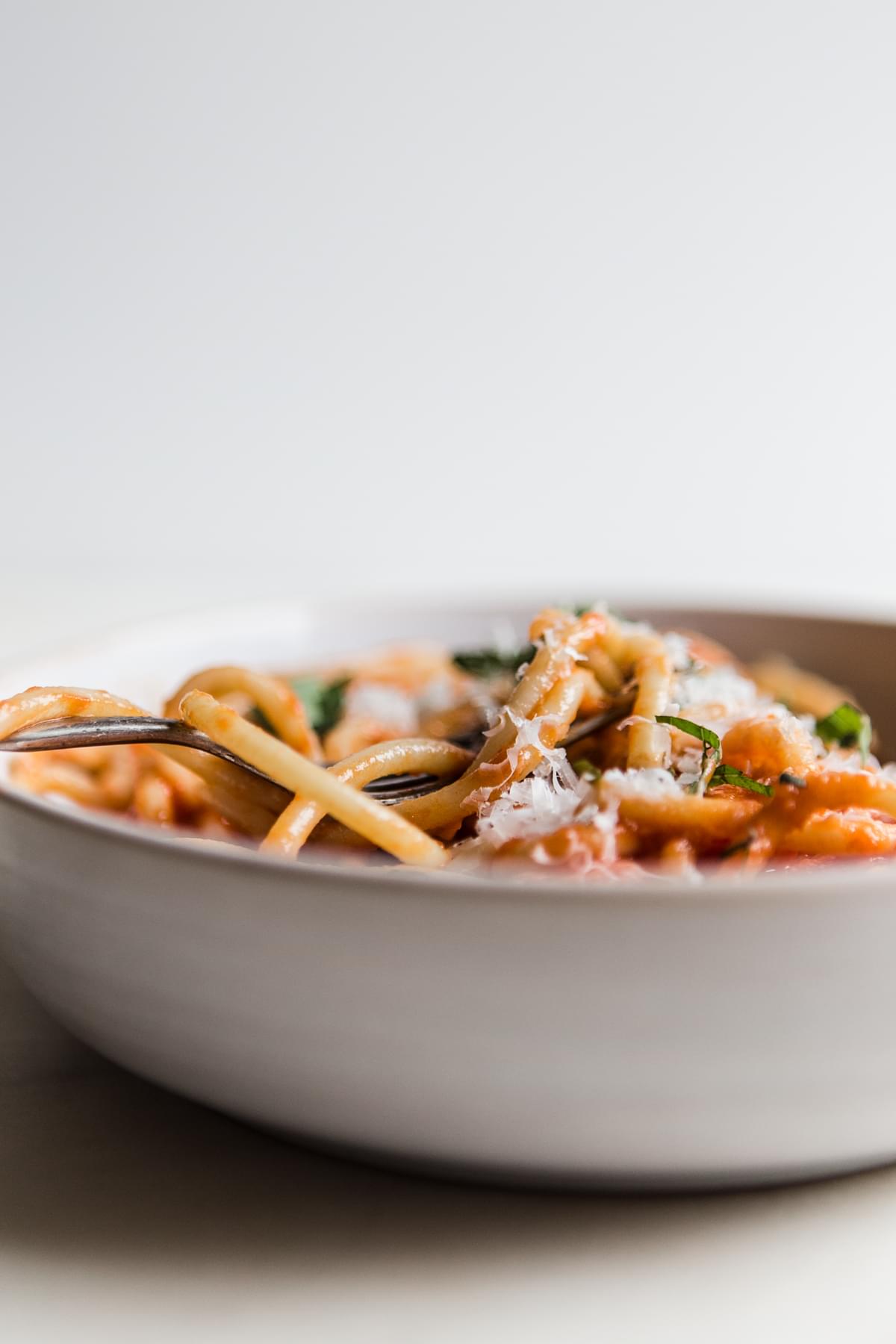 Three Ingredient Tomato Sauce pomodoro sauce with noodles in a bowl with fresh basil and parmesan cheese