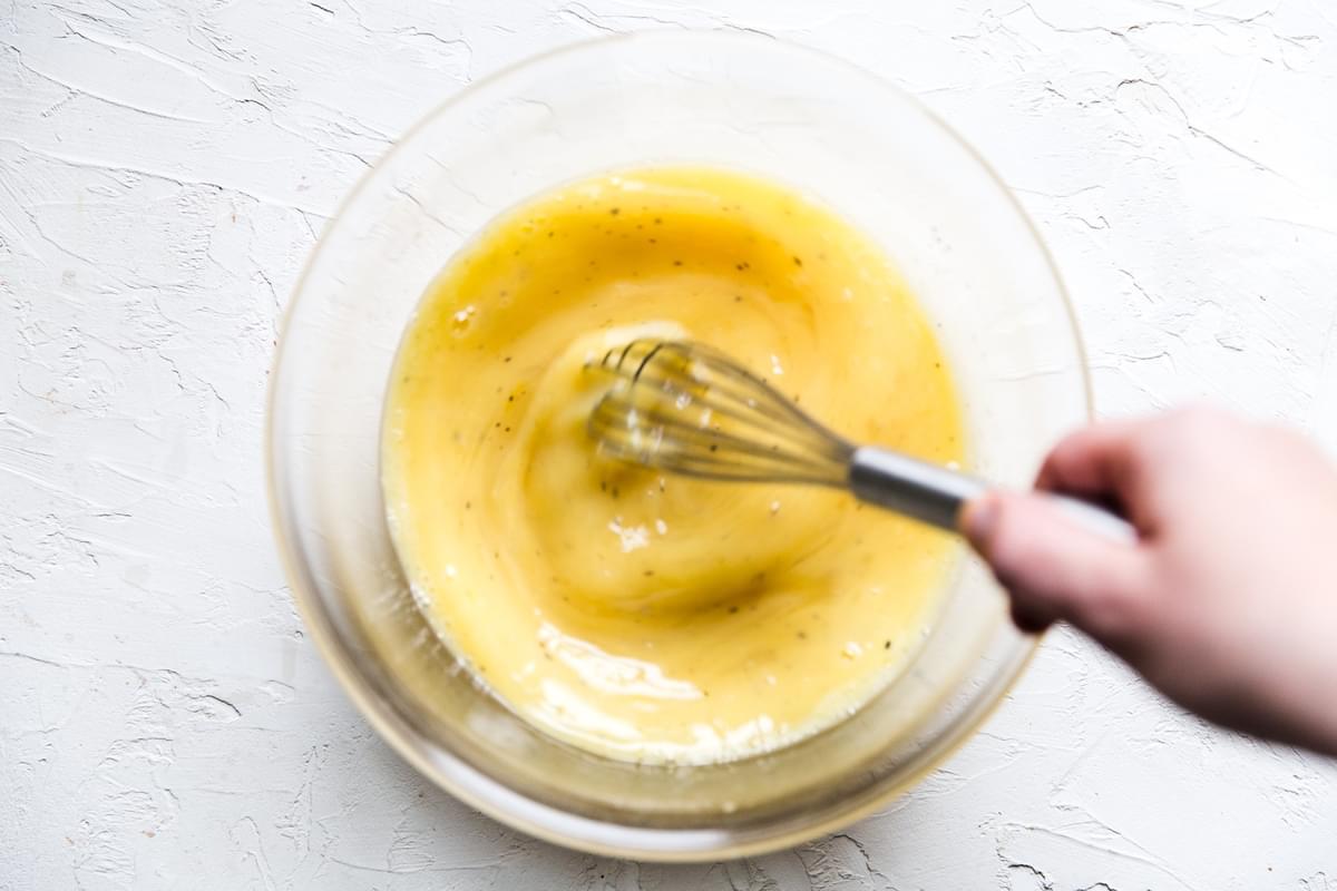 hand whisking eggs in a large bowl with a whisk