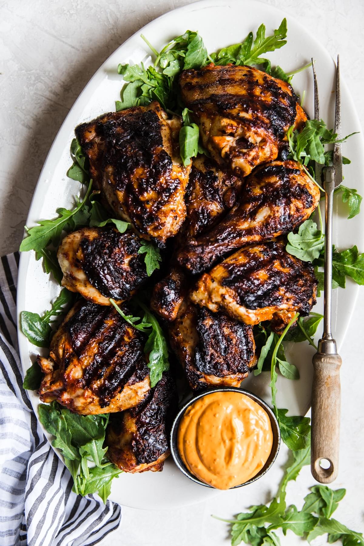 easy homemade harissa grilled bone-in chicken thighs on a platter with harissa aioli