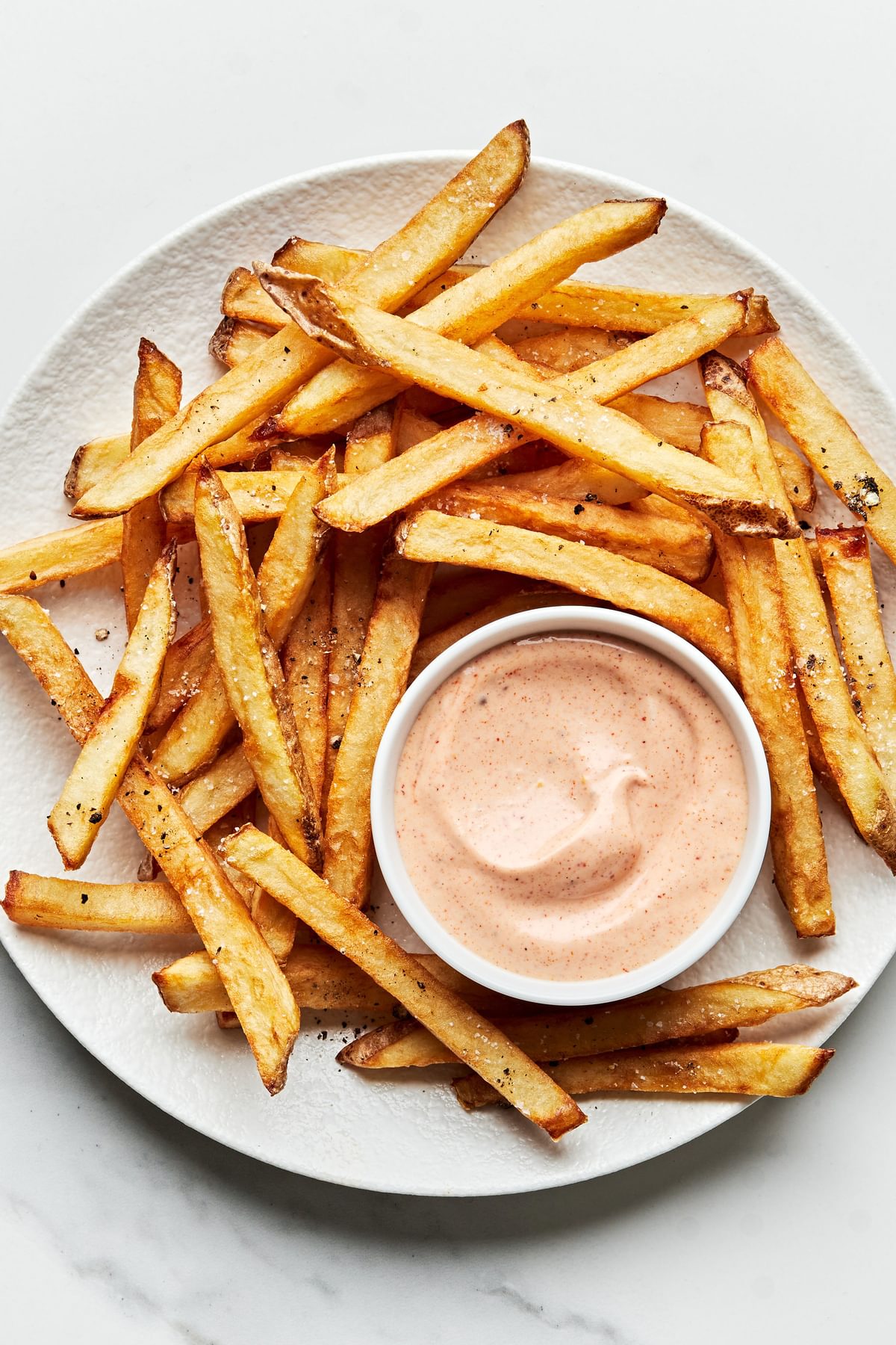 homemade french fries on a plate with a bowl of homemade fry sauce for dipping