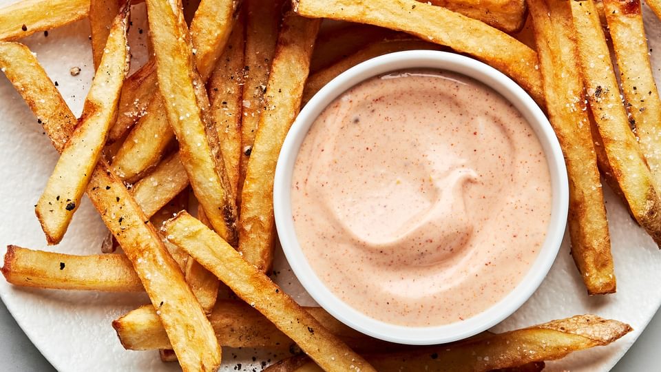 homemade french fries on a plate with a bowl of homemade fry sauce for dipping