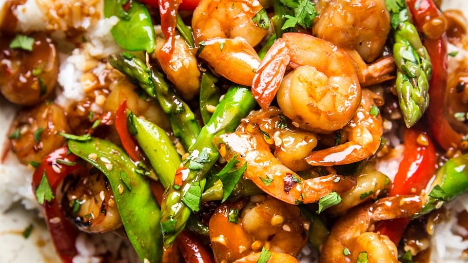 Garlic Shrimp Stir Fry with snow peas and bell peppers over rice on a plate