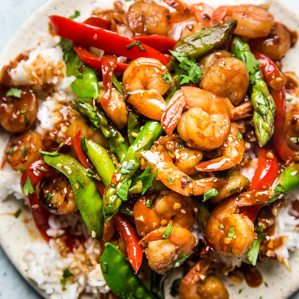 Garlic Shrimp Stir Fry with snow peas and bell peppers over rice on a plate