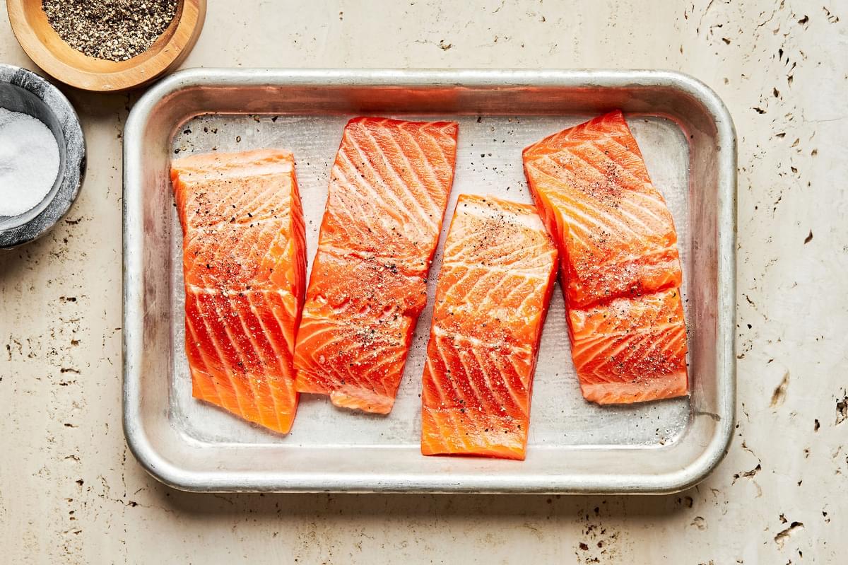 4 (4 ounce) raw salmon fillets on a baking sheet seasoned with salt and pepper