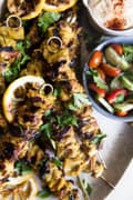 Grilled Chicken Shawarma Kebab skewers with lemon, hummus and a tomato cucumber salad