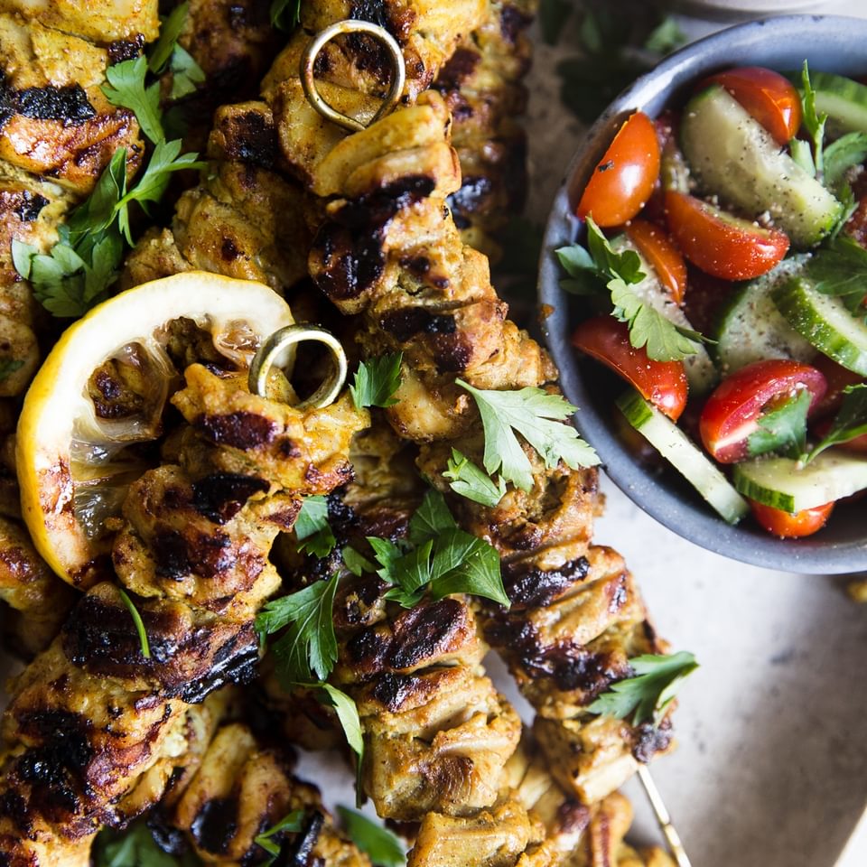 Grilled Chicken Shawarma Kebab skewers with lemon, hummus and a tomato cucumber salad