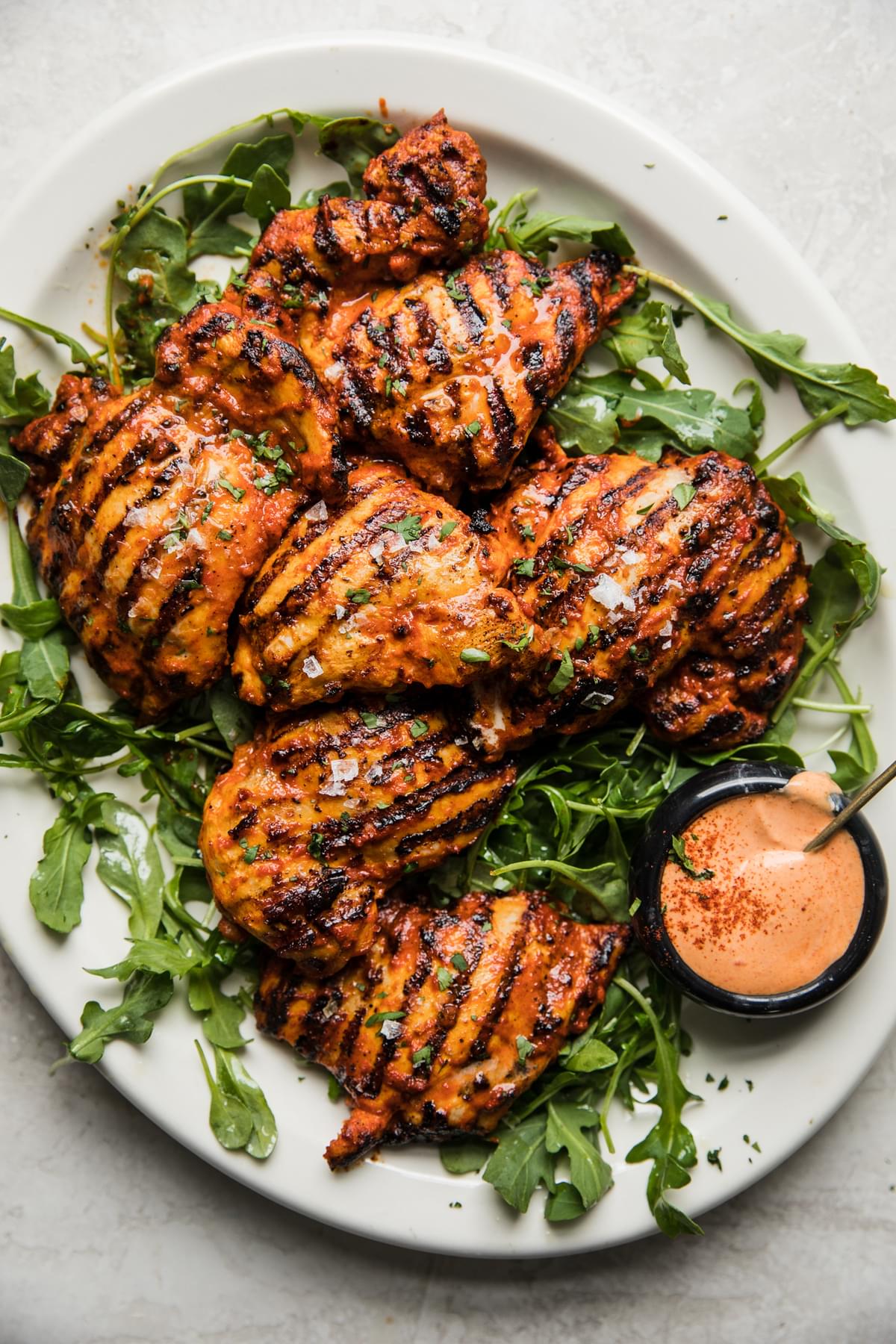 grilled harissa chicken on a plate with arugula and harissa mayonnaise
