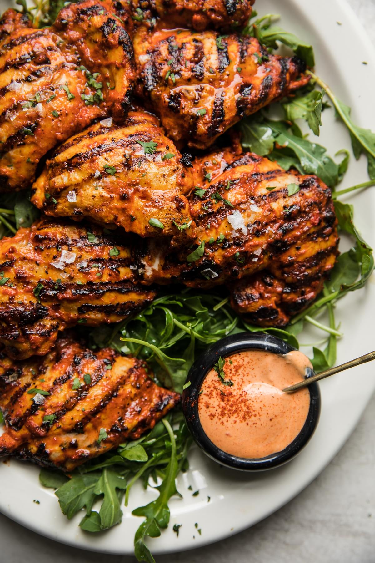 grilled harissa chicken on a plate with arugula and harissa mayonnaise