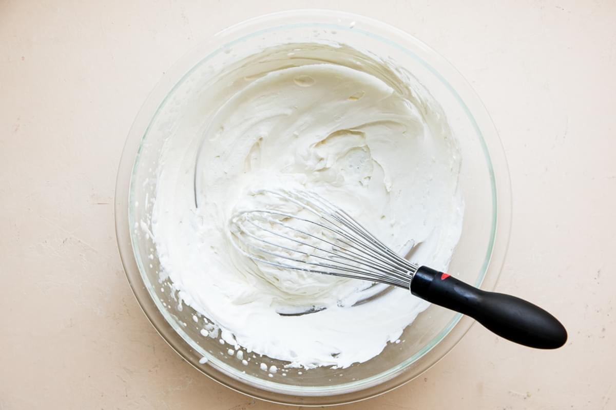 heavy cream whipped in a bowl with a whisk