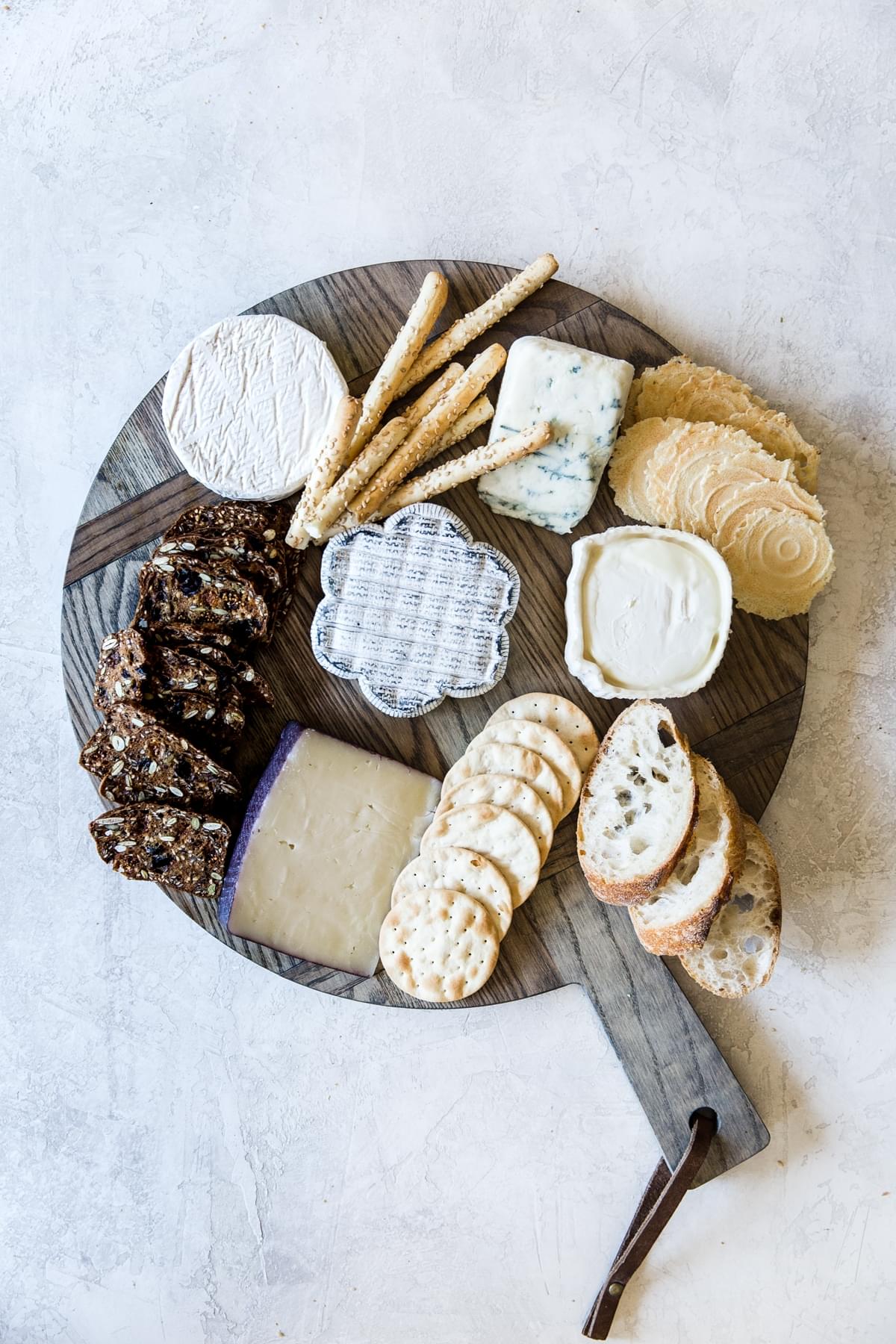 cheese and crackers and breads on a wooden cheese board