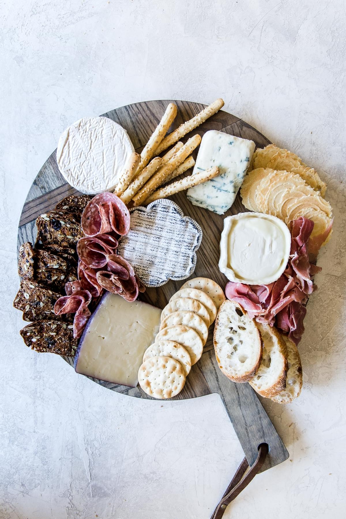cheese, meats and crackers on a wooden platter