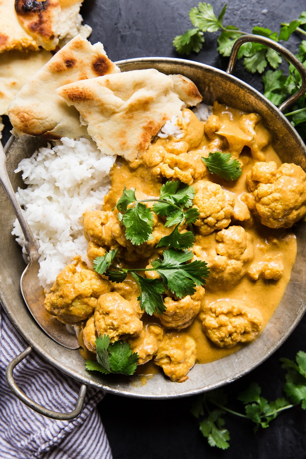 creamy Indian cauliflower curry with rice and torn naan in a large serving bowl