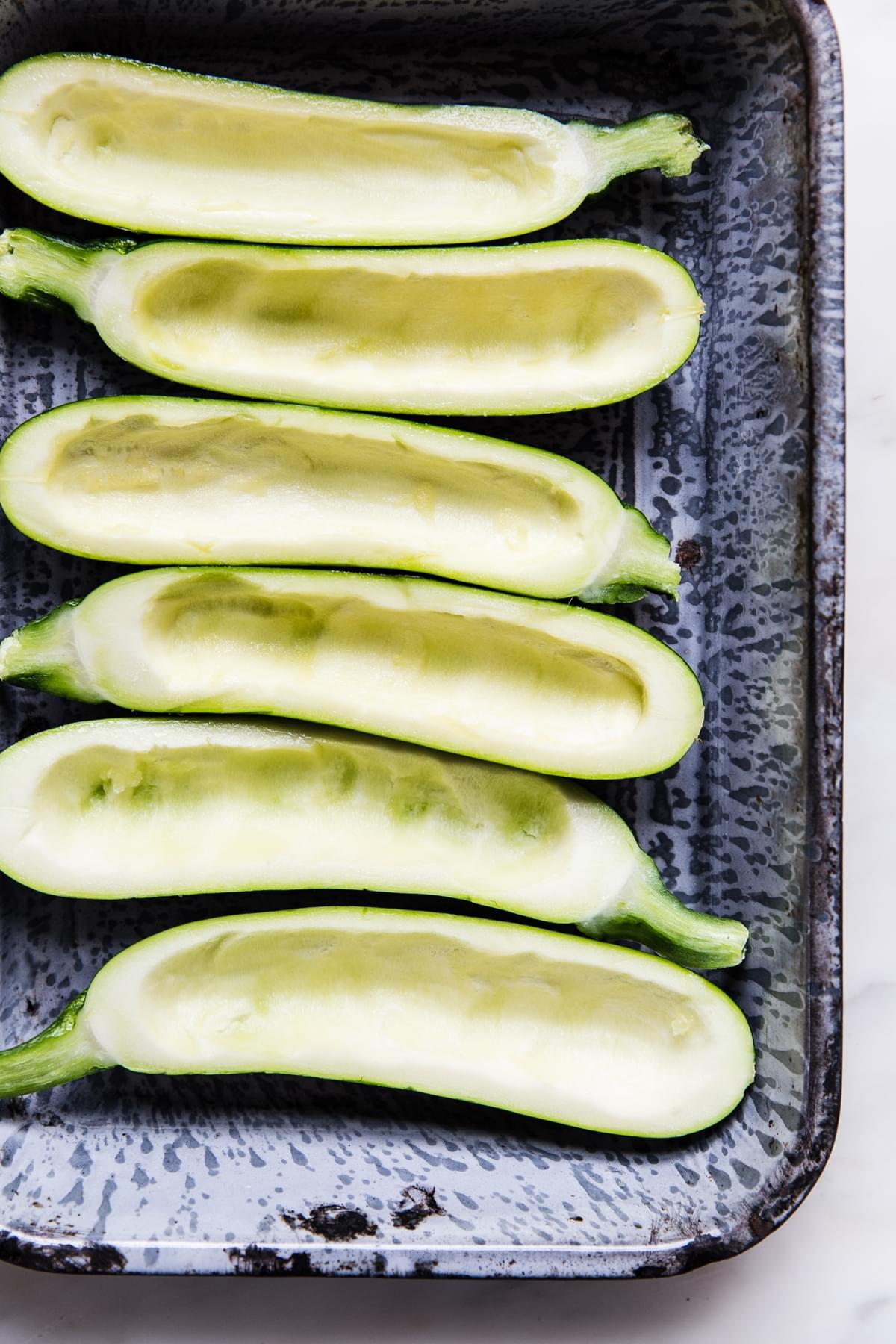a baking dish with zucchini halves