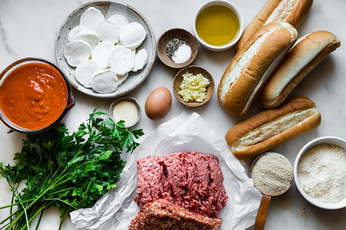 ingredients laid out for meatball sub sandwich ground beef ground sausage, bread crumbs, parsley, marinara sauce, mozzarella