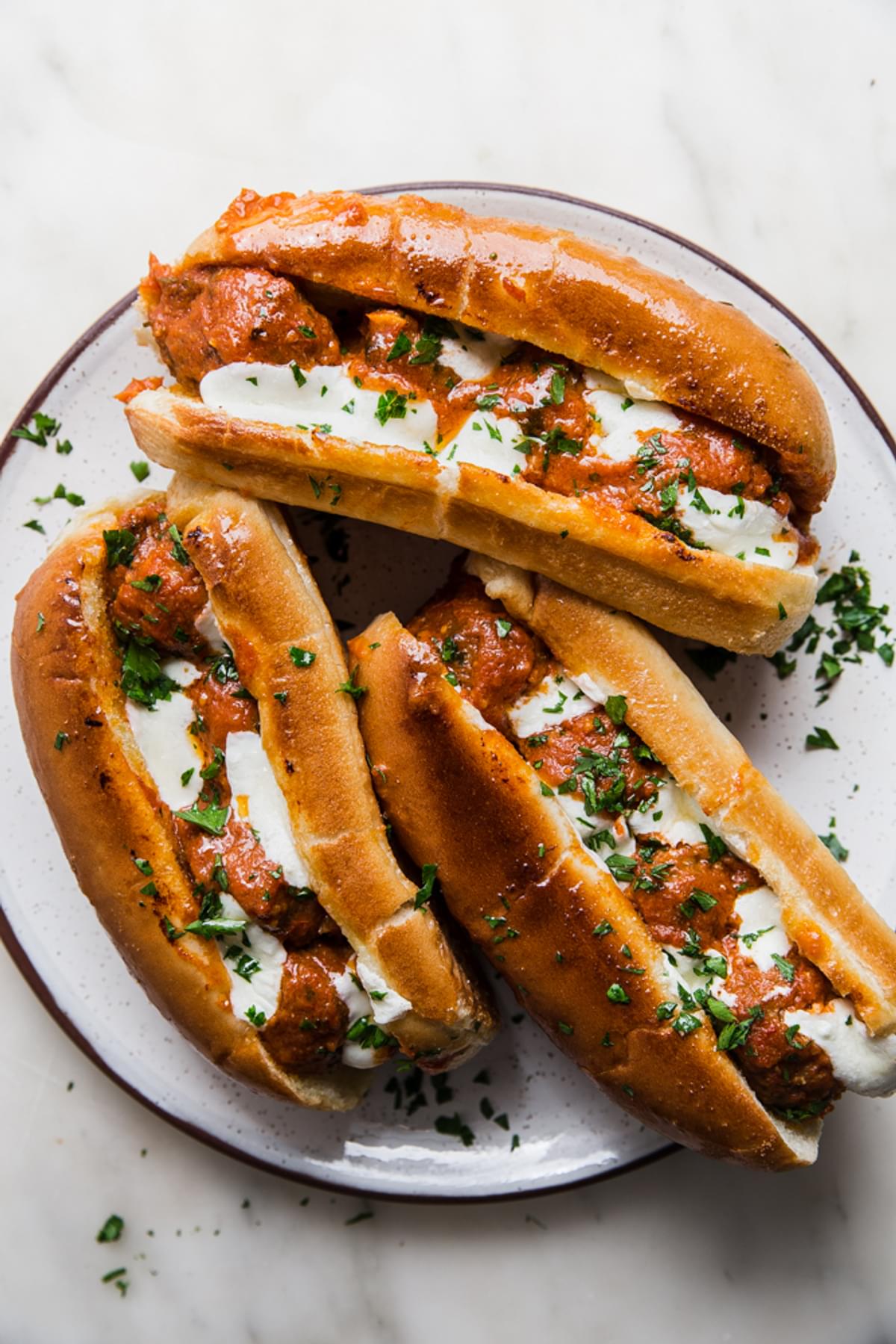 meatball sub sandwich with mozzarella and parsley on a plate
